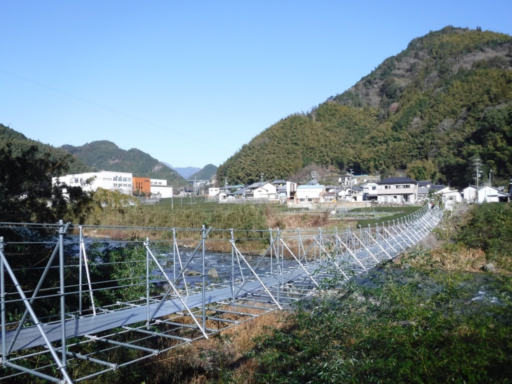 Hillside view in Okitsu region in Shimizu district in Shizuoka city. Tea gardens and townview beyond the suspension bridge over a clear stream.